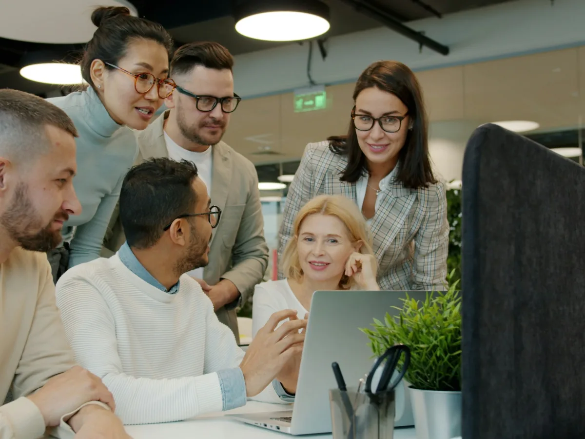 A team of professionals gathered around a laptop, smiling