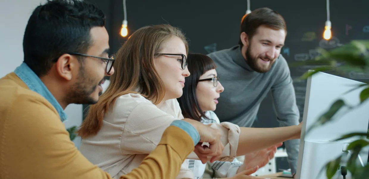 Students smile while working together at a computer during a cohort session